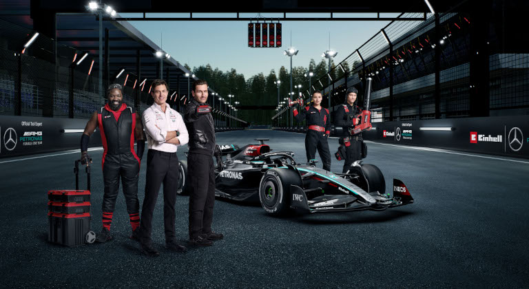 five e team members stand around formula 1 car