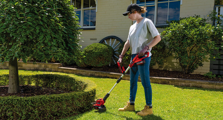 woman is trimming the lawn with a Einhell lawn trimmer